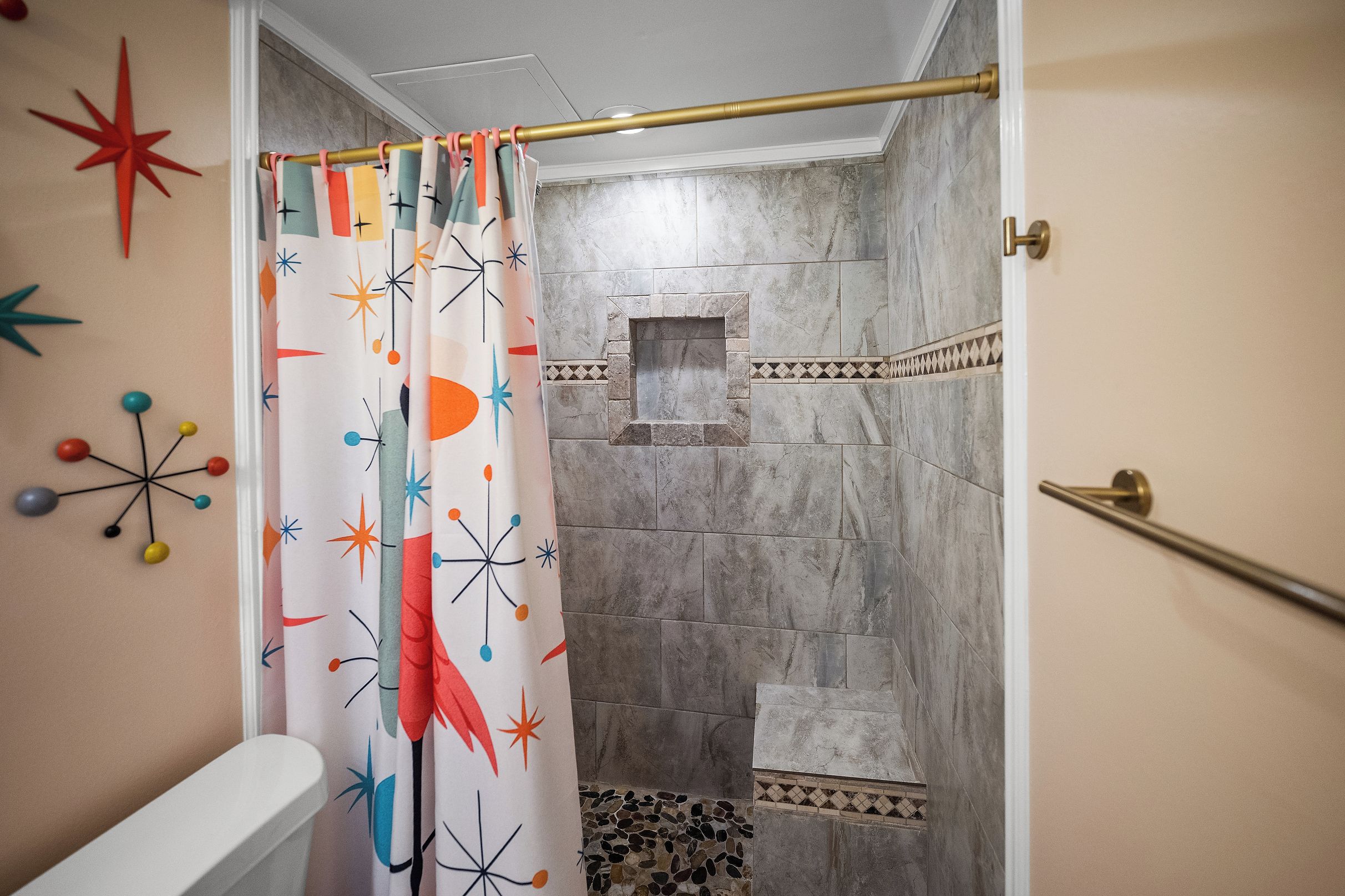 Une salle de bain comprenant un espace douche, des toilettes et un mur orné d’un motif décoratif en forme d’étoile.