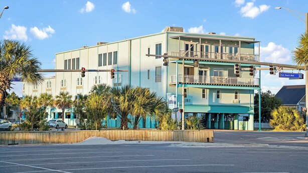 Un edificio de varios pisos con techo plano y un balcón en el segundo nivel, con una señal de calle que indica 'East Beach Blvd'.