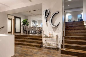 A modern interior with a staircase, a dining area, and a wall with a large letter 'PC'.