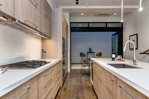 A modern kitchen with a central island, built-in appliances, and a view into the dining area.