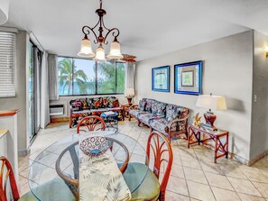 A spacious living area with a glass dining table, two sofas, and a chandelier.