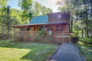 A rustic cabin with a porch, surrounded by trees.