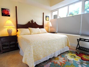 A bedroom with a large bed, two bedside lamps, a wooden nightstand, and a colorful floral rug.