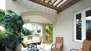 A covered patio area with a table and chairs, surrounded by greenery and a view of the outdoors. - Palms at Wailea #205 Fully Remodeled, Ground Floor Unit, Shared Hot Tub, A/C (Wailea)