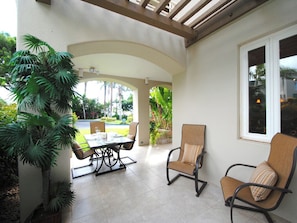 Enjoy a peaceful meal or relaxation in this serene outdoor space with a table and two chairs, surrounded by lush greenery.