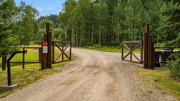 Un camino de tierra que conduce a una entrada con portón y un letrero que indica un hábitat de vida silvestre.