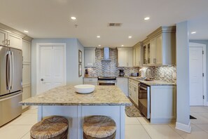 A modern kitchen with a central island, built-in appliances, and a patterned backsplash.