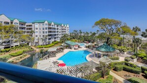 A resort with a large swimming pool, multiple guest buildings, and a view of the ocean. - This superbly appointed four-bedroom villa overlooks the beautiful beach (Hilton Head Island)
