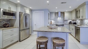 A modern kitchen with stainless steel appliances, a marble island, and a tiled backsplash. - This superbly appointed four-bedroom villa overlooks the beautiful beach (Hilton Head Island)