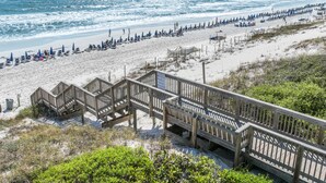 A beach with wooden boardwalks, beach umbrellas, and lounge chairs.