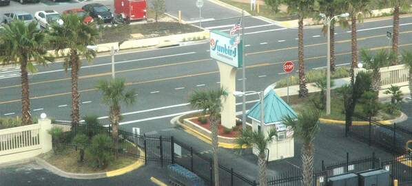 Vista de la calle con un letrero de Sunbird Condominiums, una señal de parada y un pequeño edificio con techo azul.