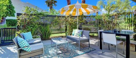 An outdoor patio area with a seating arrangement, a table, and a decorative umbrella.