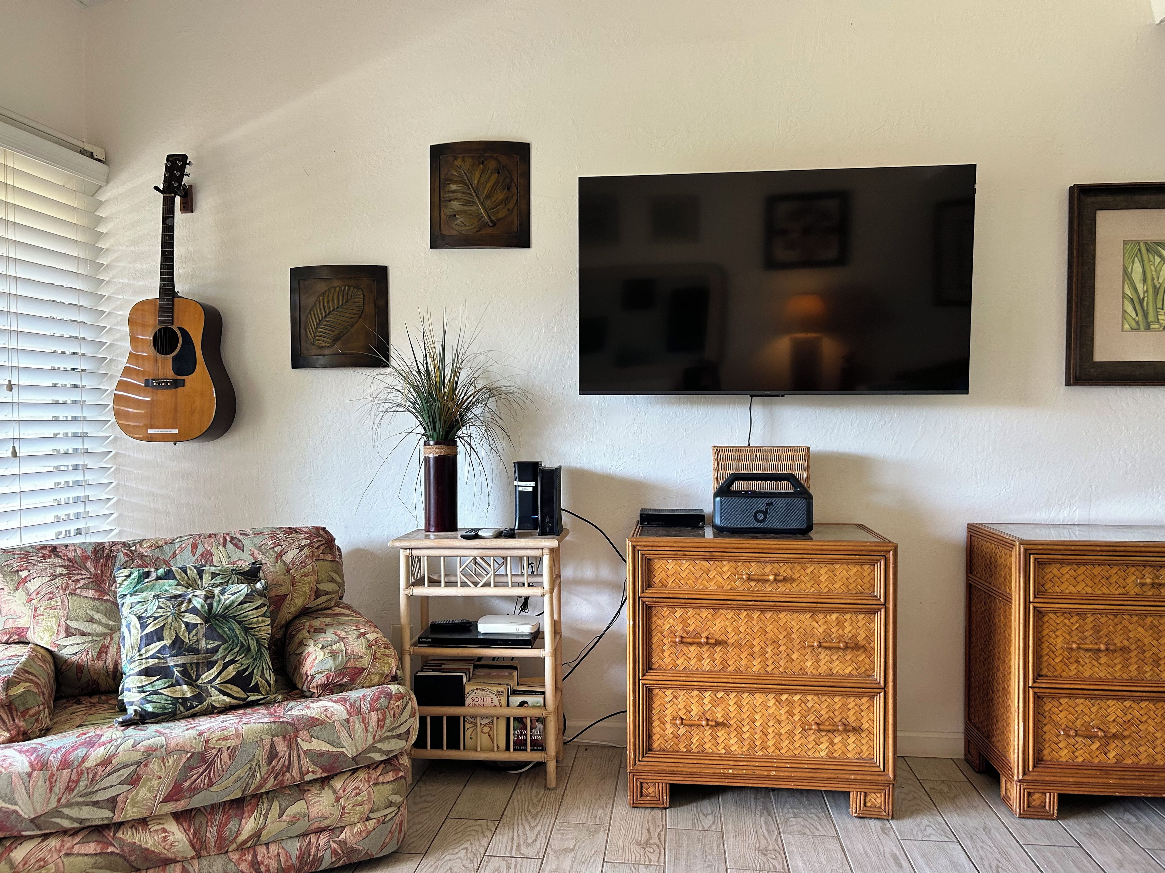 Un salon avec un canapé, une guitare, un téléviseur et une table basse.