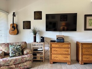 A living room with a couch, a guitar, a TV, and a coffee table.