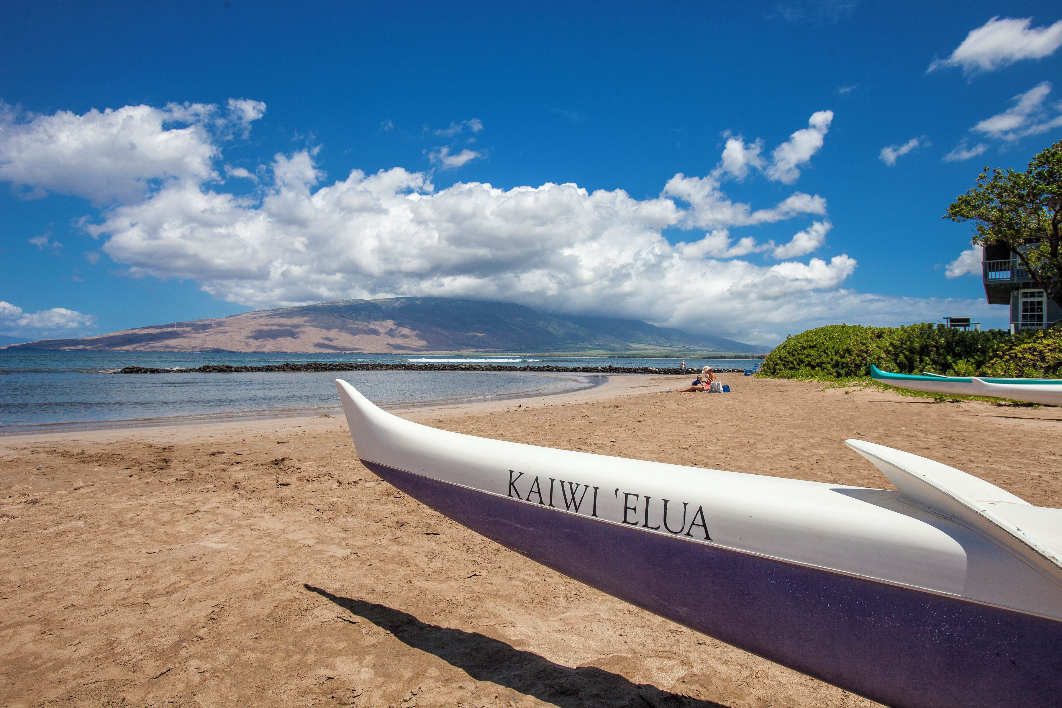A beach with a canoe labeled 'KAIWI ELUA' and a building with a balcony.