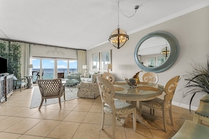 Relax in this spacious living area with a high ceiling, featuring a round mirror and dining table with chairs.