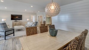 A modern living room with a wooden dining table, patterned chairs, and a unique hexagonal pendant light.