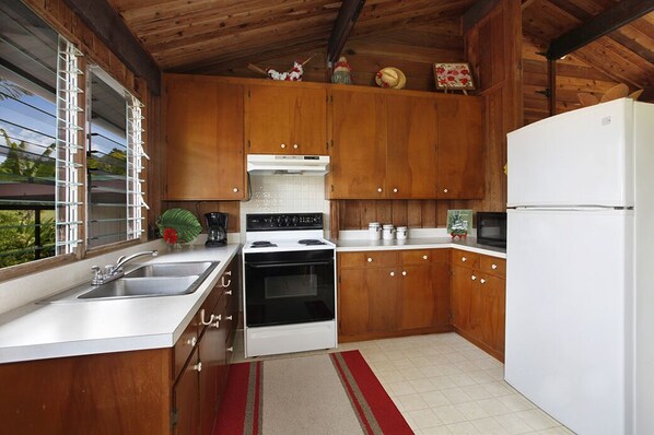 Una cocina con armarios de madera, un refrigerador blanco, una estufa y un fregadero.