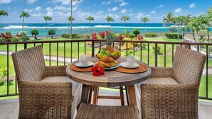 Ein Balkon mit Korbstühlen, einem runden Tisch und einer Obstschale mit Croissants.