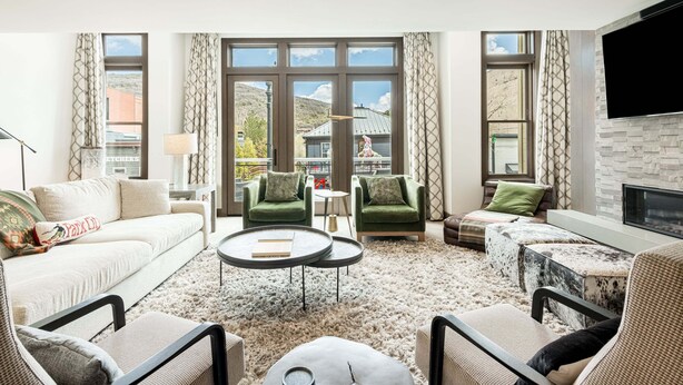 A modern living room with a sofa, two green armchairs, a coffee table, and a fireplace.