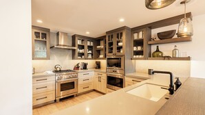 A modern kitchen with built-in appliances, wooden cabinets, and a large island with a sink.