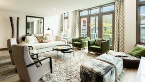 A spacious living room with a large window, a sofa set, a coffee table, and a fireplace.