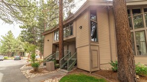 A two-story building with a beige exterior, large windows, and a small front porch with a staircase. - Upgraded, Light-Filled St. Moritz Villa 325 (Mammoth Lakes)