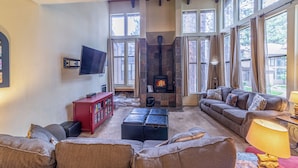 A cozy living room with a fireplace, a sofa, a red cabinet, and a television. - Upgraded, Light-Filled St. Moritz Villa 325 (Mammoth Lakes)