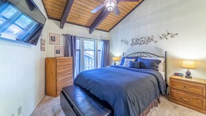 A bedroom with a large bed, a wooden bench, a ceiling fan, and a wall-mounted light. - Upgraded, Light-Filled St. Moritz Villa 325 (Mammoth Lakes)