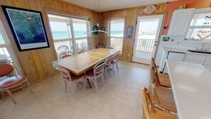 A room with a wooden interior, a dining table with chairs, a kitchen area, and a view of the beach through large windows. - Large 5 bedroom, 3-1/2 bath BEACHFRONT Home, Just Steps to Peaceful Beach (Port Saint Joe)