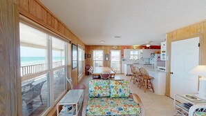 A spacious living area with a large window overlooking the ocean, a dining table, and a kitchen area. - Large 5 bedroom, 3-1/2 bath BEACHFRONT Home, Just Steps to Peaceful Beach (Port Saint Joe)