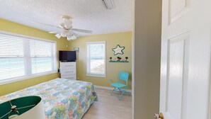 A bedroom with a bed, a ceiling fan, a dresser, a chair, and a window with blinds. - Large 5 bedroom, 3-1/2 bath BEACHFRONT Home, Just Steps to Peaceful Beach (Port Saint Joe)