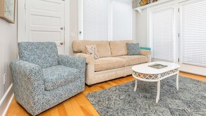 Un salon avec un fauteuil à motifs, un canapé beige et une table basse blanche.
