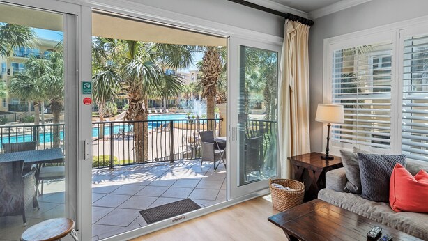 A balcony with a pool view, a sofa, a lamp, and a table.