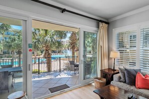 Un balcón con vista a la piscina, un sofá, una lámpara y una mesa.