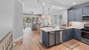 A modern kitchen with a central island, stainless steel appliances, and a view to a dining area.