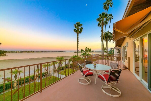 Enjoy a serene river view from this balcony with a round table and two comfortable chairs.