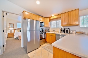 Enjoy cooking in this well-equipped kitchen with a refrigerator, oven, microwave, cabinets, and sink.