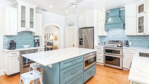 A modern kitchen with white cabinetry, a central island, and stainless steel appliances. - Butler Beach Cottage | Pet-Friendly, Quiet Neighborhood (Tybee Island)