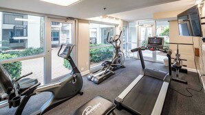 A gym with treadmills, elliptical machines, and a bench.