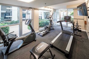 A gym with treadmills, elliptical machines, and a bench.