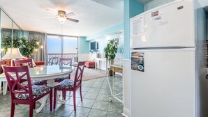 A compact living space with a dining area, a refrigerator, and a ceiling fan.