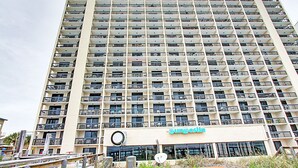 A high-rise building with multiple balconies, a sign reading "Sunrise," and a view of the surrounding area.