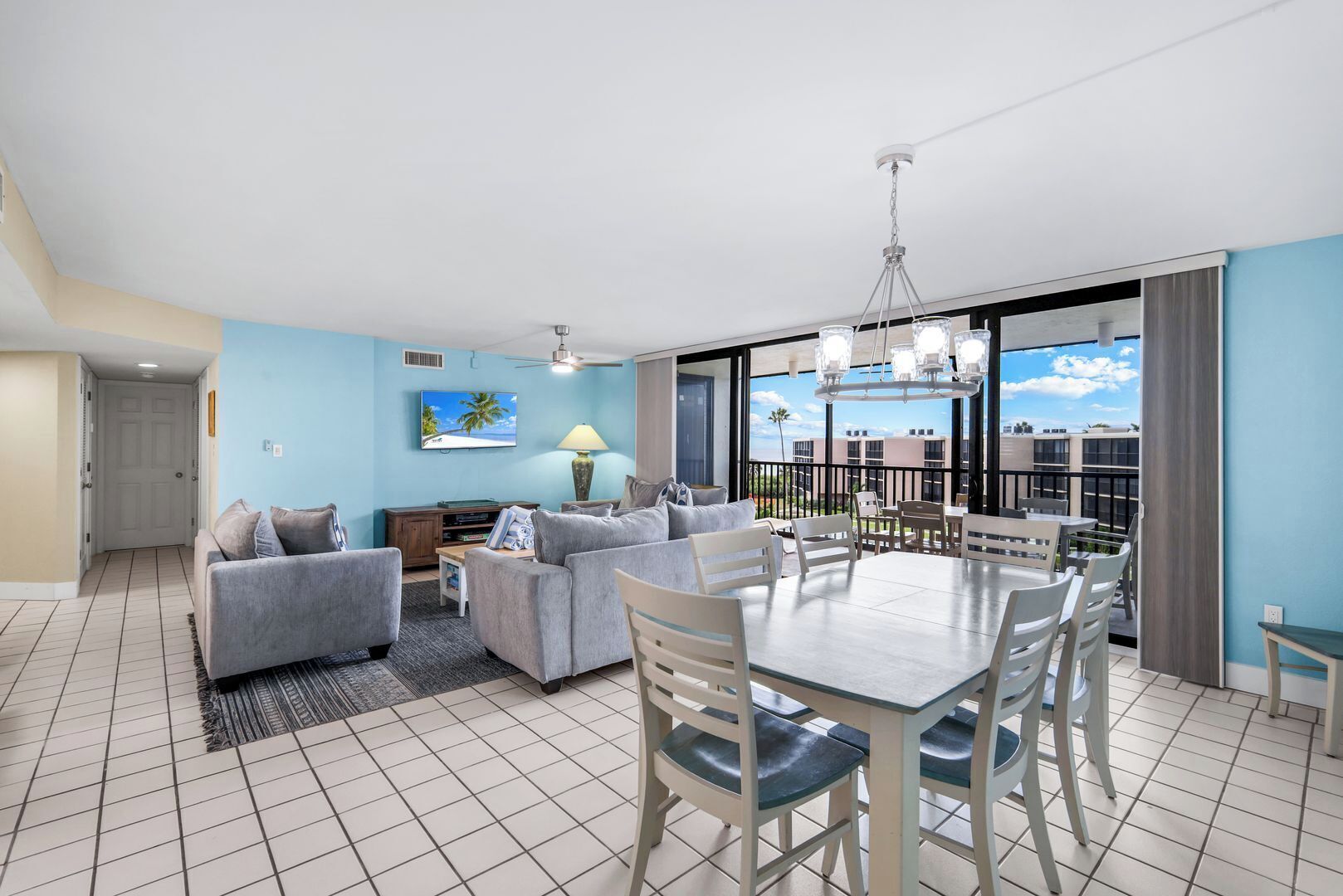 A modern living room with a dining area, a TV, and a balcony with a view.