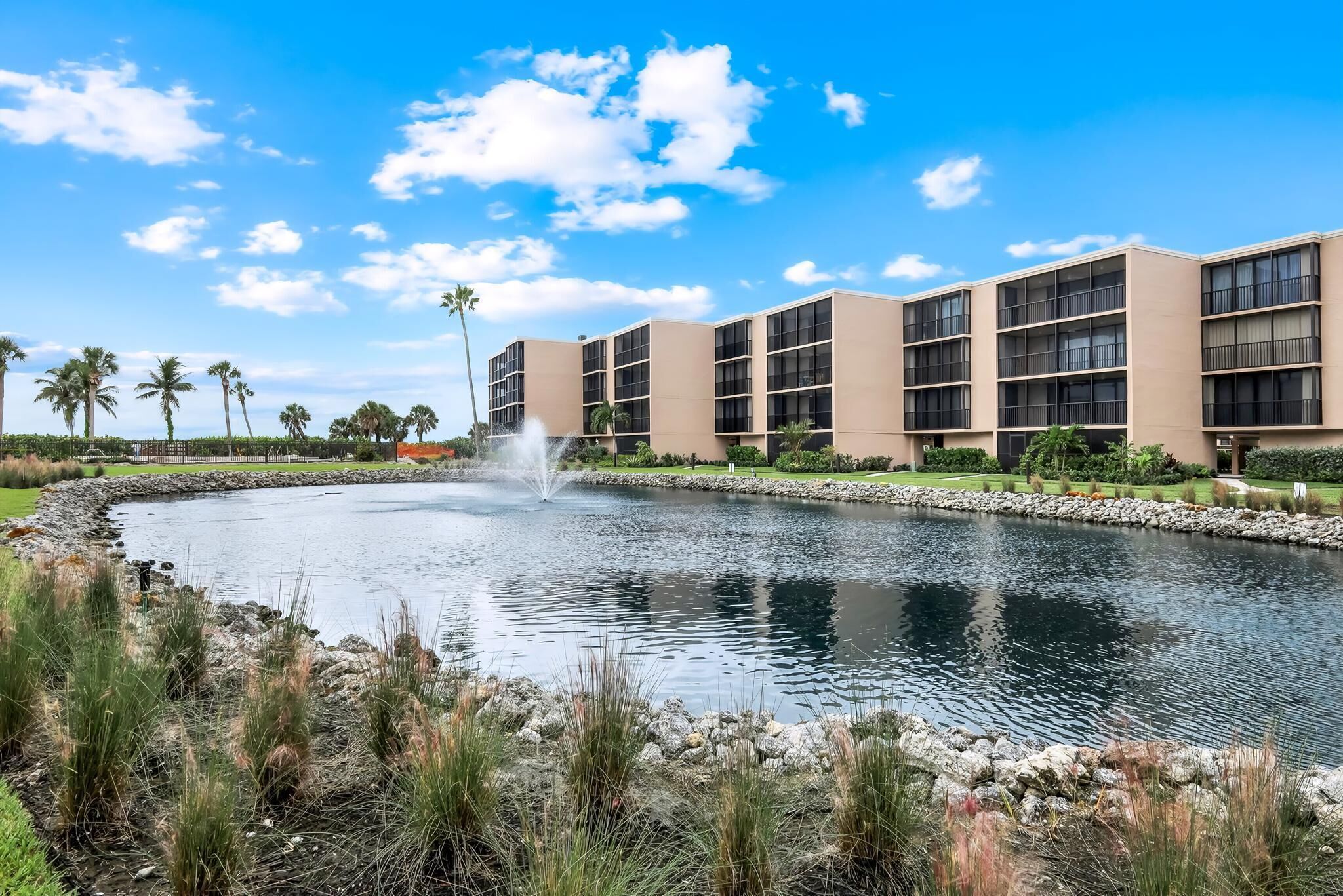 A modern building with a central water feature, surrounded by well-maintained landscaping and palm trees.