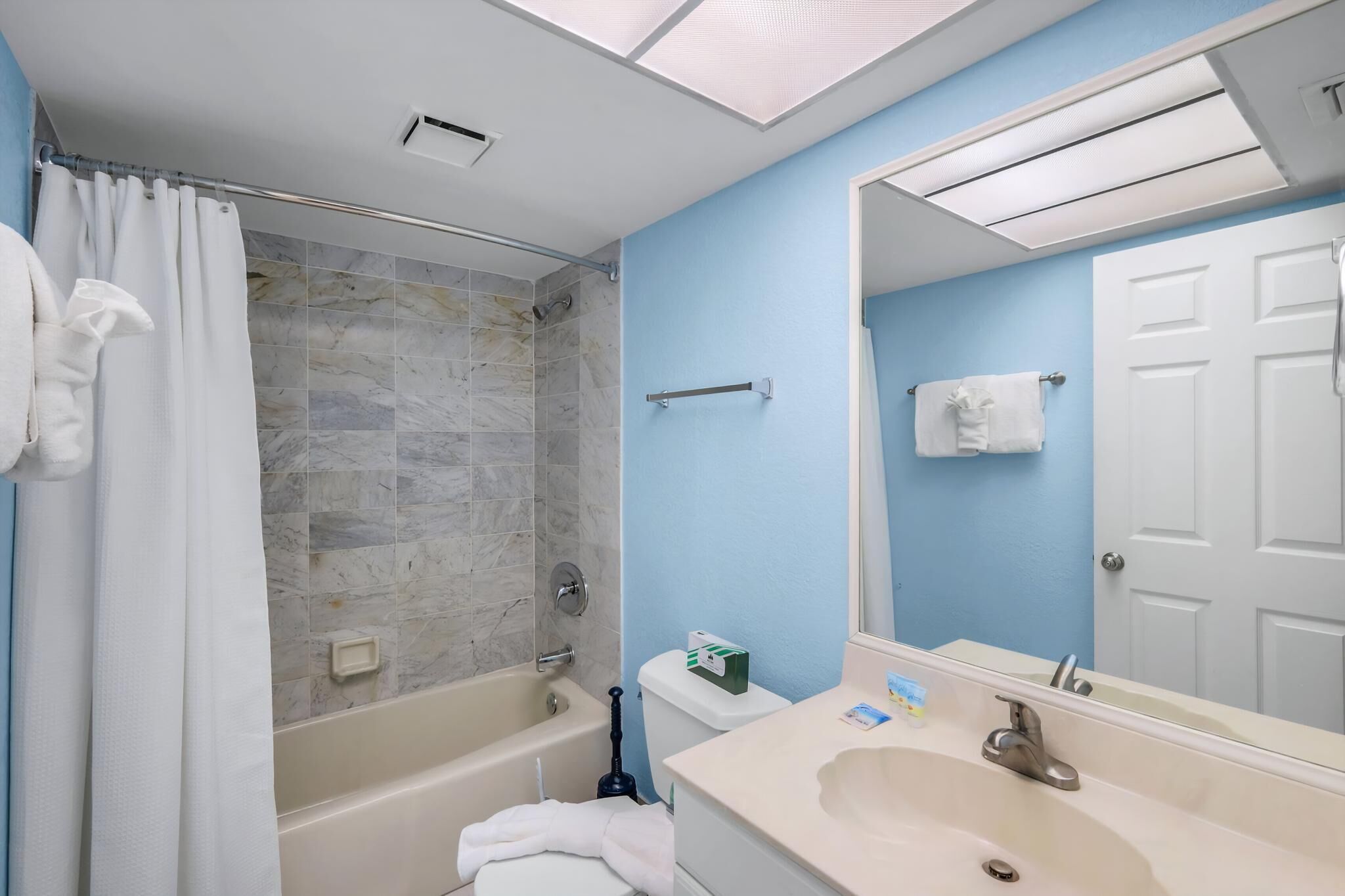 A bathroom with a bathtub, shower, sink, and a large mirror.