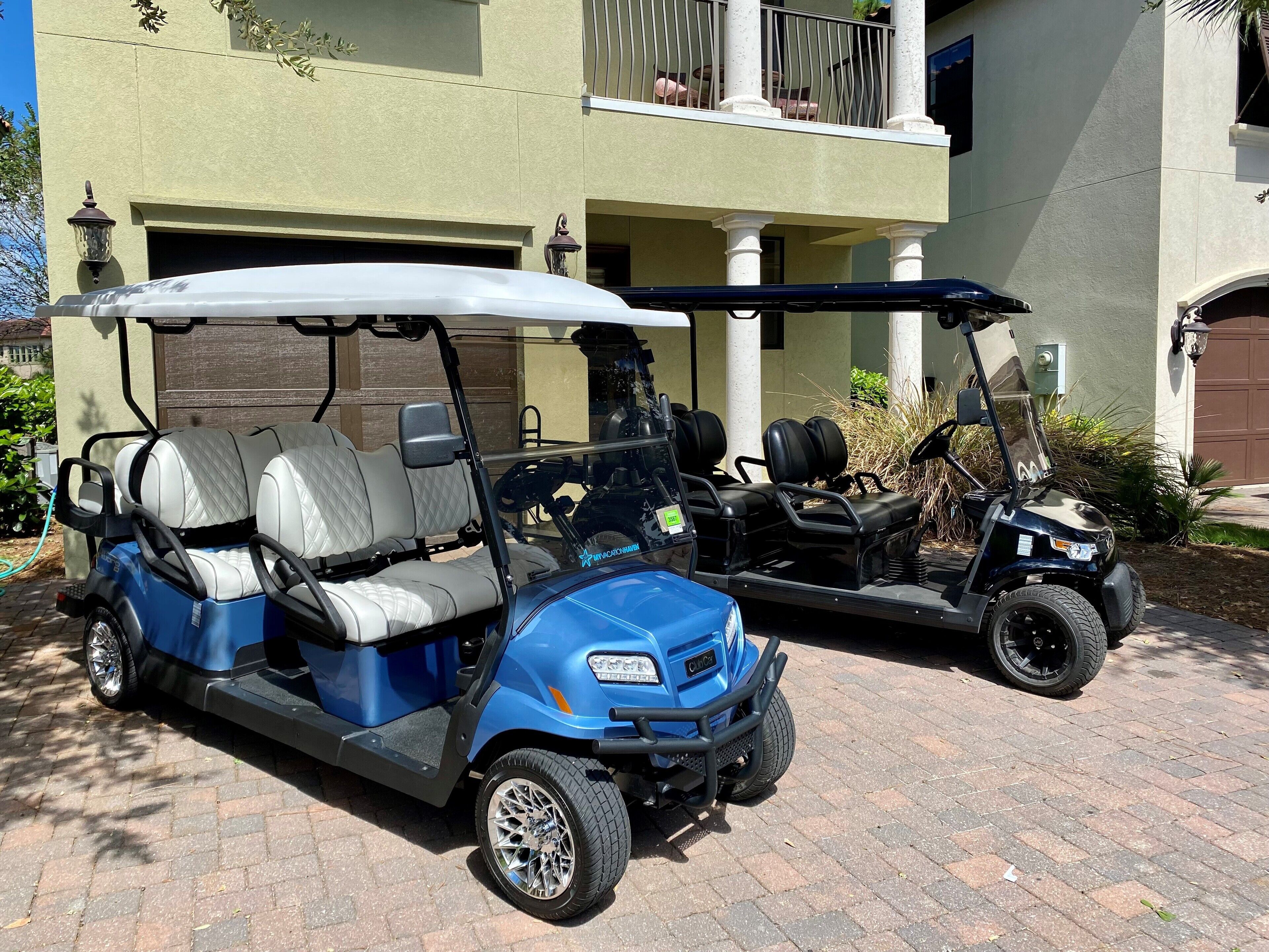 Deux voiturettes de golf sont garées devant un bâtiment doté d’un garage et d’un balcon.