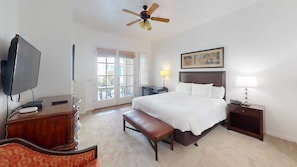 A hotel room with a bed, a desk, a television, a ceiling fan, and a window.