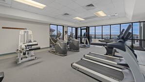 Ein Fitnessraum mit Laufbändern, Crosstrainern und Gewichten.