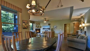 A spacious living room with a large round table, comfortable seating, a fireplace, and a scenic view through the window. - Corral at Breckenridge Raven Condo: Soaking Tub, Views (Breckenridge)